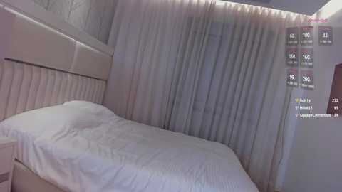 Media: Video of a minimalist bedroom with a white bed, white curtains, and a white headboard. The room is dimly lit, with a virtual chat window displaying user information on the right.