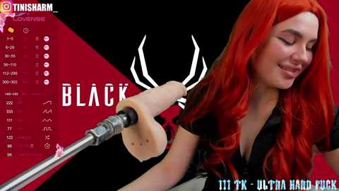 Media: A video of a red-haired woman with long wavy hair, wearing a black blouse, holding a microphone, and speaking into it, set against a red and black background with text and icons.