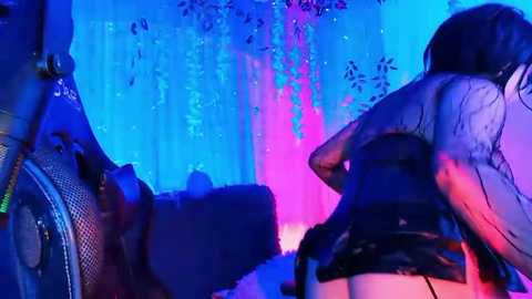 Media: Video of a nightclub scene with two women in black latex outfits, one with long dark hair, the other with short hair, under blue and pink lights.