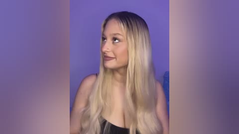 Media: Video of a smiling, light-skinned woman with long, platinum blonde hair, wearing a black top, against a purple and white gradient background.