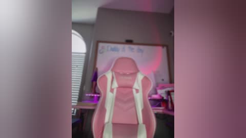 Media: A video of a pink gaming chair in a dimly lit room, with a whiteboard in the background and a partially visible window with closed blinds.