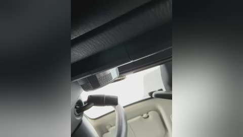 Media: Video of a car interior showing a black dashboard with a central air vent and a gray armrest. The steering wheel and parts of the seat are visible.