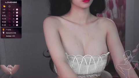 Media: A video of an East Asian woman with pale skin, long black hair, and full red lips. She wears a white, lace-trimmed strapless top. Background shows a dimly lit room with a digital overlay displaying \"LOUNGE\" and user statistics.