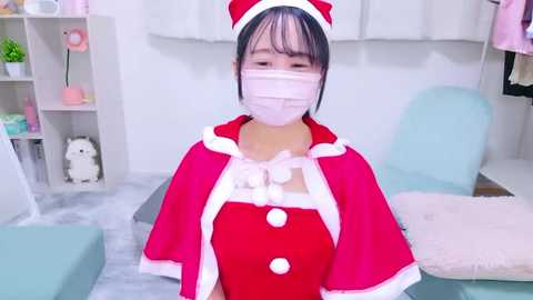 Media: Video of an Asian woman in a red nurse costume with a white mask, standing in a bright, minimalist room with light-colored furniture and decor.