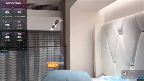 Media: Video of a modern hotel room with a white, tufted headboard, light blue pillows, and a digital temperature display showing 30\u00b0C.