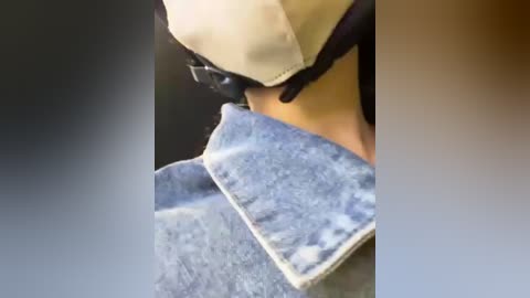 Media: Video of a person wearing a beige mask and dark gloves, holding a blue denim shirt with white stains, suggesting laundry or cleaning.