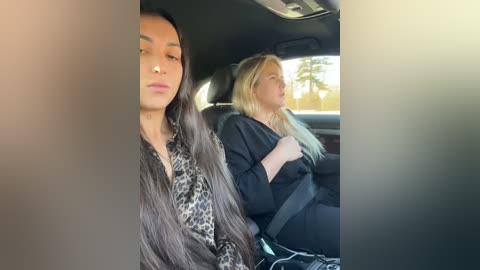 Media: Video of two women in a car, one with long dark hair, the other with blonde hair, both wearing black jackets, looking out windows.