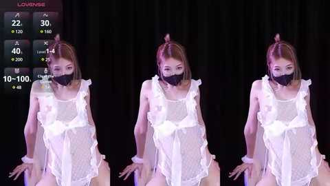 Media: A video featuring a slender Asian woman with short brown hair, wearing a sheer white maid outfit and a black face mask, posing seductively against a black backdrop.