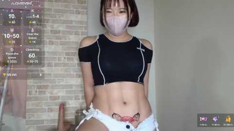 Media: A video of a young Asian woman with a short bob haircut, wearing a black crop top and white shorts, standing in front of a brick wall, with a mask on her face, and a virtual overlay showing health metrics.