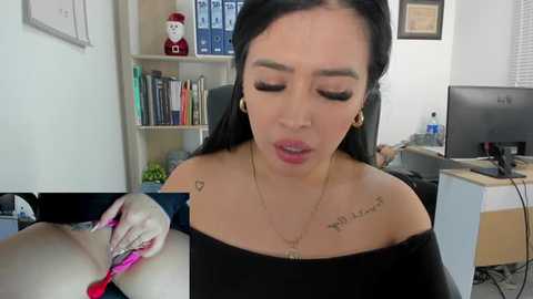 Media: Video of a Latina woman with long black hair, wearing a black off-shoulder top, and gold hoop earrings, getting her eyebrows waxed in an office with bookshelves, computer, and decorative figurines.