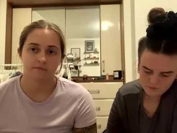 Media: Video of two young women with light skin, one with brown hair in a bun, the other with brown hair tied back, in a modern kitchen.