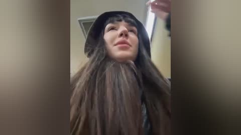 Media: A close-up video of a person with long, dark brown hair, partially covered in a white, fluffy material, possibly a wig. The background is blurred, suggesting an indoor setting.