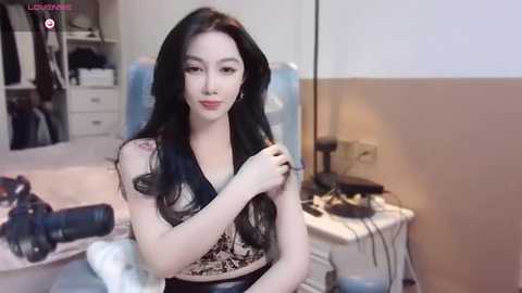 Media: A video of an East Asian woman with long black hair, fair skin, and a slender physique, wearing a leopard-print top, standing in a cluttered bedroom with a bed, shelves, and a desk visible in the background.