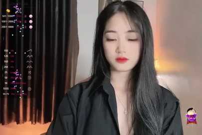 Media: Video of a young Asian woman with long black hair, wearing a black shirt, standing against a background of dark curtains.