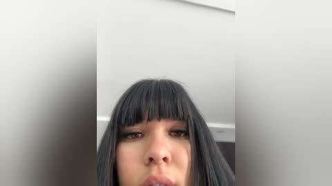 Media: Video of a young Asian woman with long, straight black hair and bangs, wearing dark eye makeup, pouting, against a plain white background.