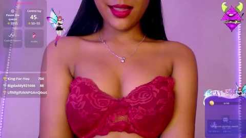 Media: Video of a young woman with long black hair, wearing a red lace bra, smiling with bright red lipstick. Background features digital overlays of fairy wings and chat messages.