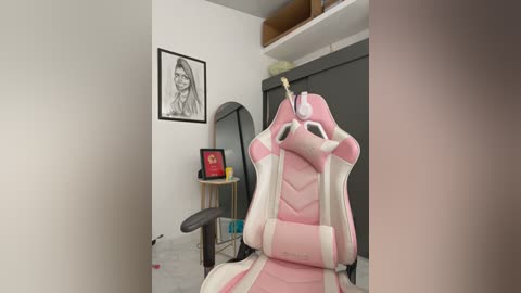 A video of a pink gaming chair with a unicorn horn, set in a minimalist, white-walled room with framed artwork and a black desk.