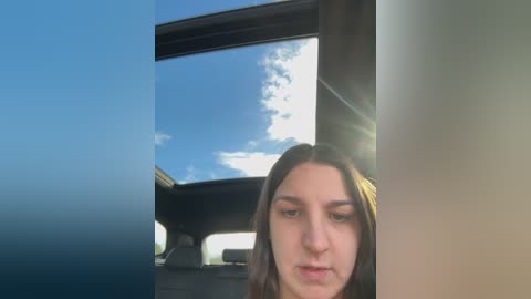 Media: A video of a young woman with long brown hair, slightly blurred, looking out the car window at a clear blue sky with scattered clouds.