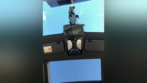 Media: A video of a car's dashboard, featuring a small, cartoonish Batman figure in a glass dome, above the speedometer and tachometer, with a clear blue sky visible through the windshield.