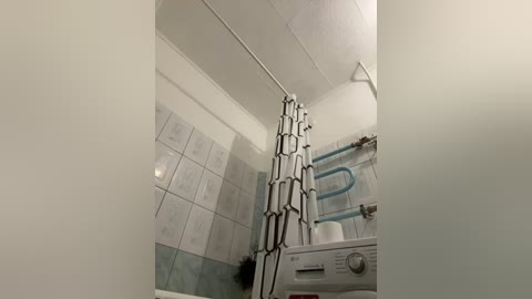 Media: A video of a small, modern bathroom with a white sink, blue and white tiled walls, and a black shower curtain rod.