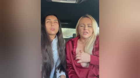 Media: Video of two women in a car: a dark-haired woman with long hair in a light blue shirt, and a blonde woman in a red blouse, both with closed eyes, seemingly in a state of ecstasy.