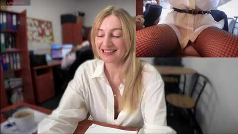 Media: Video of a smiling blonde woman in a white blouse, fishnet stockings, and lace panties, sitting at a desk in a cluttered office with bookshelves and computer monitors. Close-up inset of her legs in stockings.