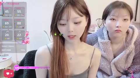 Media: Video of two East Asian women in casual attire; one with long brown hair, the other with short hair, both with light skin tones, in a modern, brightly lit room.