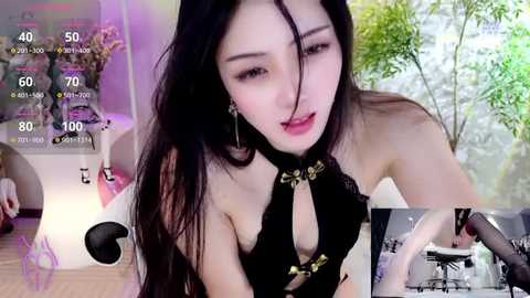 Media: A video of an Asian woman with long black hair, wearing a black halter top, in a modern living room with greenery and purple lighting.