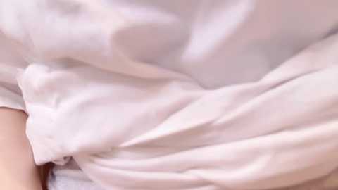 Media: A close-up video of a person's legs covered in white, wrinkled sheets, creating a soft, cozy texture. The image focuses on the folds and creases of the bedding, emphasizing comfort and relaxation.