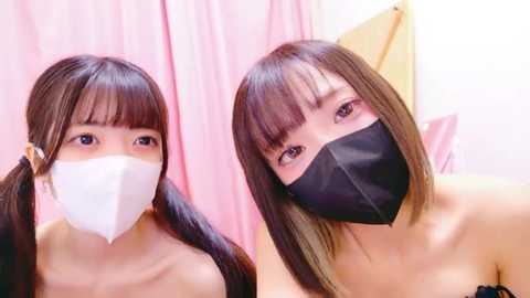 Media: Video of two East Asian women with straight brown hair, wearing white face masks and black face masks, in a pink-tinted room with soft lighting.