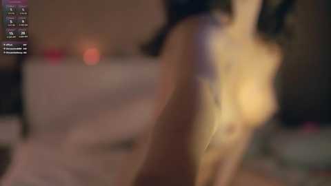 Media: A blurred video of a naked woman with light skin, small breasts, and long dark hair, seen from the side. The background is dimly lit, featuring indistinct objects.