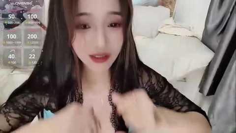 Media: A video of an East Asian woman with long black hair, fair skin, and red lipstick, wearing black lace lingerie, lying on a white bed. The background includes a digital clock displaying 10:00 AM.