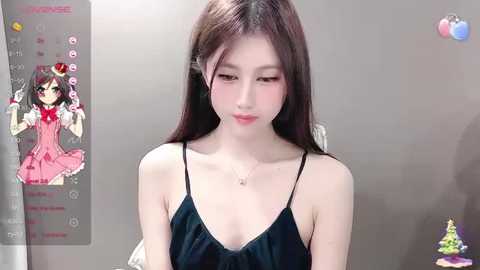 Media: Video of an East Asian woman with fair skin, long brown hair, and a slender physique. She wears a black spaghetti-strap dress, sitting in a minimalist room with a green plant on the right.