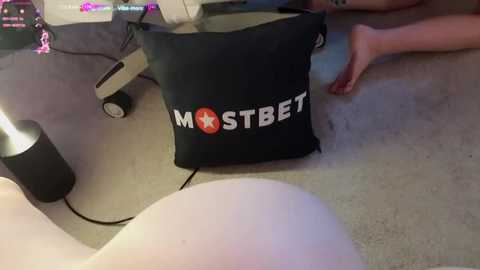 Media: Video of a black \"MostBet\" promotional bag on a beige carpet, with a person\u2019s feet and a desk chair in the background.