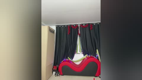 Media: Video of a modern bedroom with a black and red upholstered bed, dark curtains, and a white ceiling.