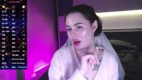 Media: Video of a pale-skinned woman with dark hair, wearing a white robe, licking her finger, in a dimly-lit room with a digital clock showing 1:31 AM.