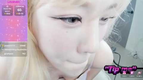 Media: A close-up video of a young, fair-skinned woman with blonde hair, wearing dramatic winged eyeliner and a white tank top, with a blurred background. The image includes a \"TIP me\" watermark.