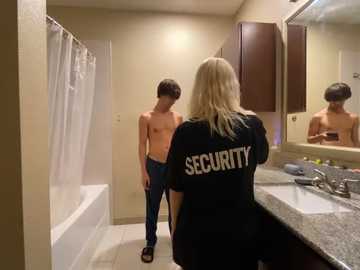 Media: Video of a shirtless teenage boy in a bathroom, wearing jeans, facing a blonde woman in a black \"Security\" t-shirt, standing at a sink.