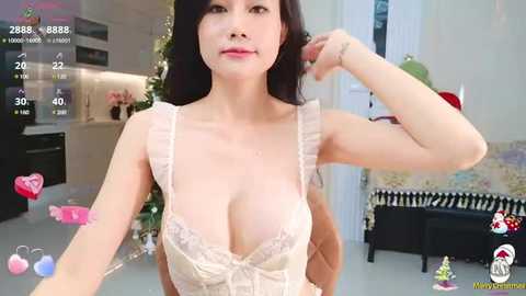 Media: A video of an Asian woman with long black hair, wearing a revealing, pale pink lace dress with a plunging neckline, posing in a modern kitchen with festive decorations.