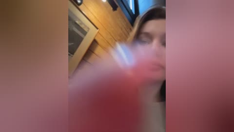 Media: A blurry video showing a woman's face and a wooden cabinet in the background, likely taken indoors.