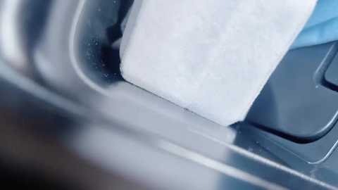 Media: A close-up video shows a white, textured bar soap being placed into a stainless steel soap dish, partially submerged in water. The image focuses on the textures and colors of the soap and dish, highlighting cleanliness and hygiene.