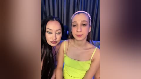 Media: Video of two young women with long, straight hair. One wears a pink headband and a neon green tank top, while the other has dark hair and a dark top.