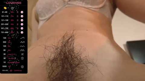 Media: Video of a person with a dark pubic hair patch, wearing a white bra, captured from a low angle. Background shows a digital screen displaying the \"Love Venues\" app interface.