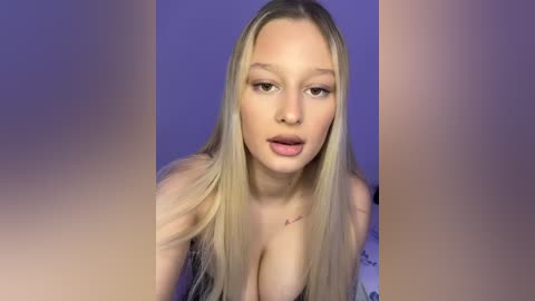 Media: A video of a fair-skinned, blonde woman with long hair, large breasts, and a subtle tattoo near her collarbone, against a blurred purple background.