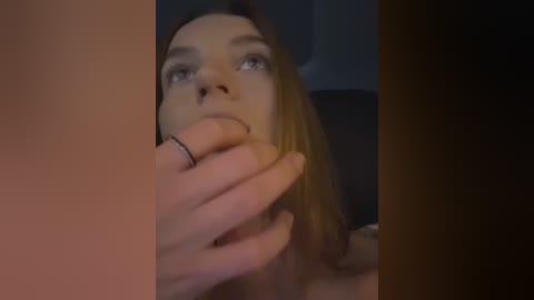 Media: Video of a young Caucasian woman with light skin and long brown hair, looking up at a man's erect penis, which she is holding with her left hand.