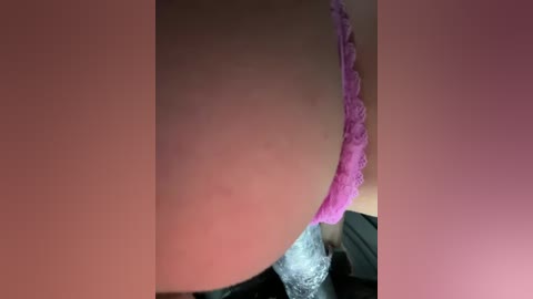 Media: Close-up video of a woman's pink lace thong, partially visible under a white liquid, possibly urine, on her skin. The image is framed by pink and white borders, suggesting it's a cropped screenshot.