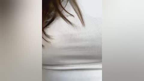 Media: A close-up video of a person's torso wearing a tight white shirt, emphasizing the fabric's stretch and revealing the contours of their body. The focus is on the upper chest and the shirt's texture.