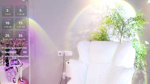 Media: Video of a minimalist room with a white armchair, a potted plant, and a digital clock displaying a rainbow effect.