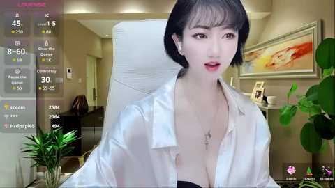 Media: A video of an East Asian woman with short black hair, wearing a semi-open white shirt revealing a black bra, sitting in a modern office.