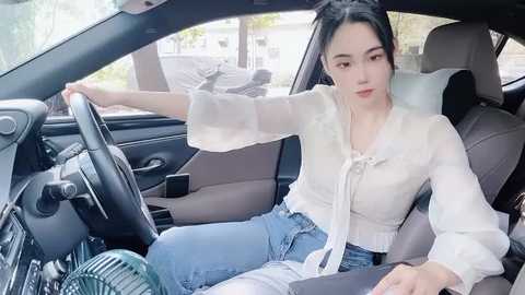 Media: A video of a young Asian woman with long black hair, wearing a white blouse and jeans, sitting in a car, steering with one hand, smiling.